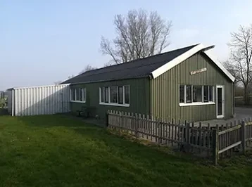 Het clubhuis ’t Rooit er op, een groen houten gebouw