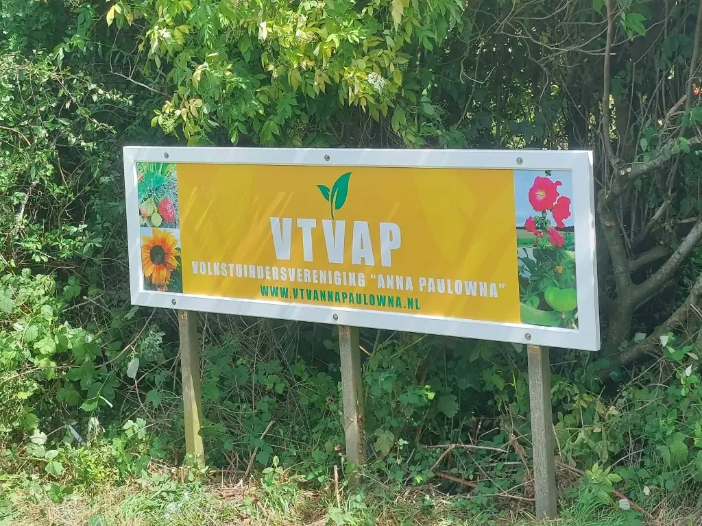 Het gele VTVAP-bord langs de weg bij de ingang van het complex