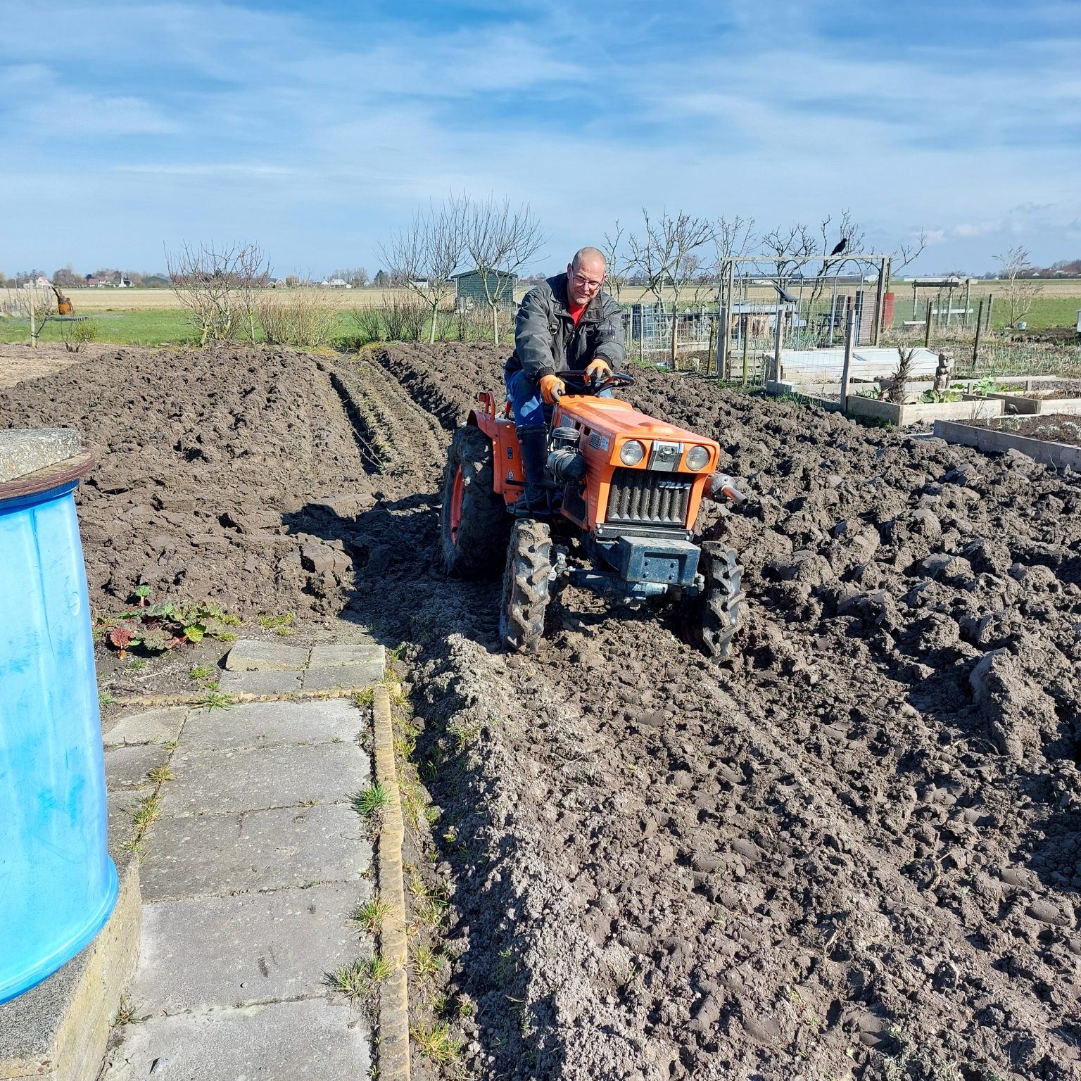 man op trekker in een moestuin